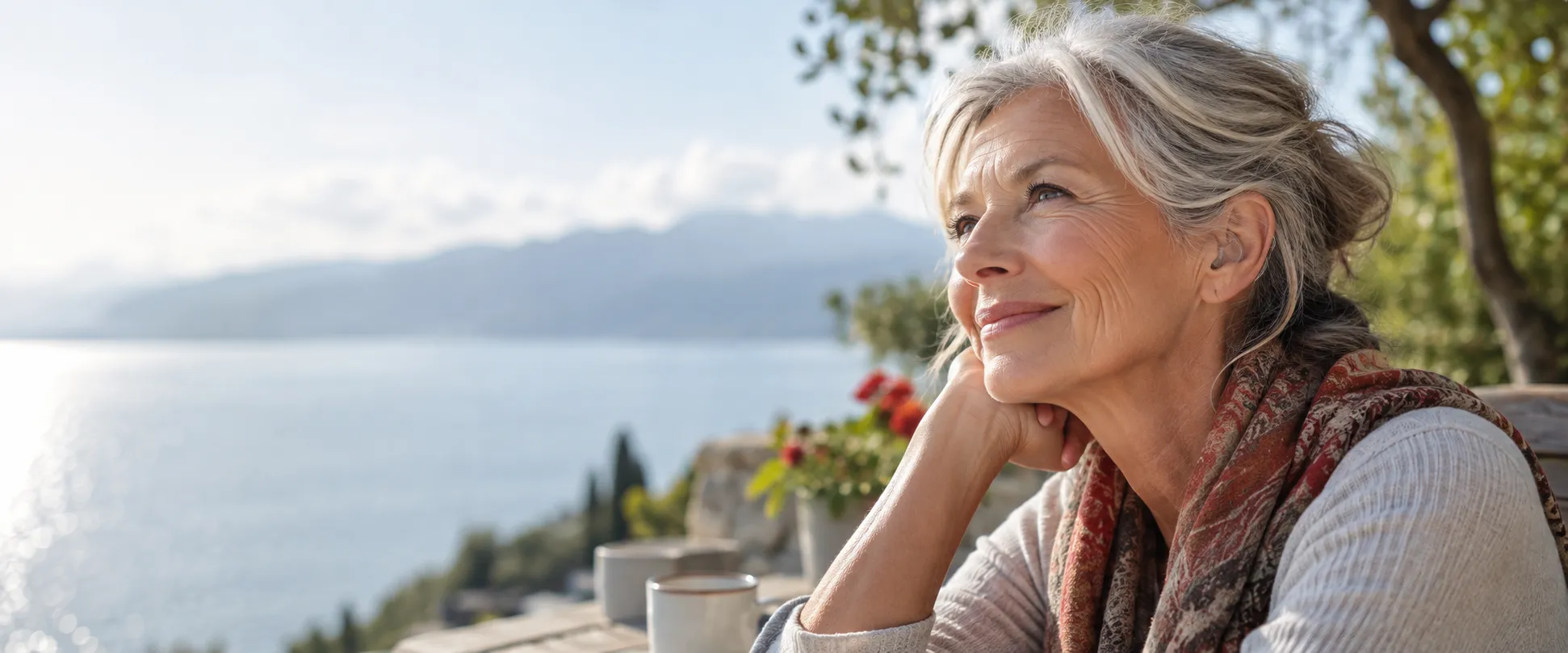 Smiling woman with a hearing aid looking out over the sea