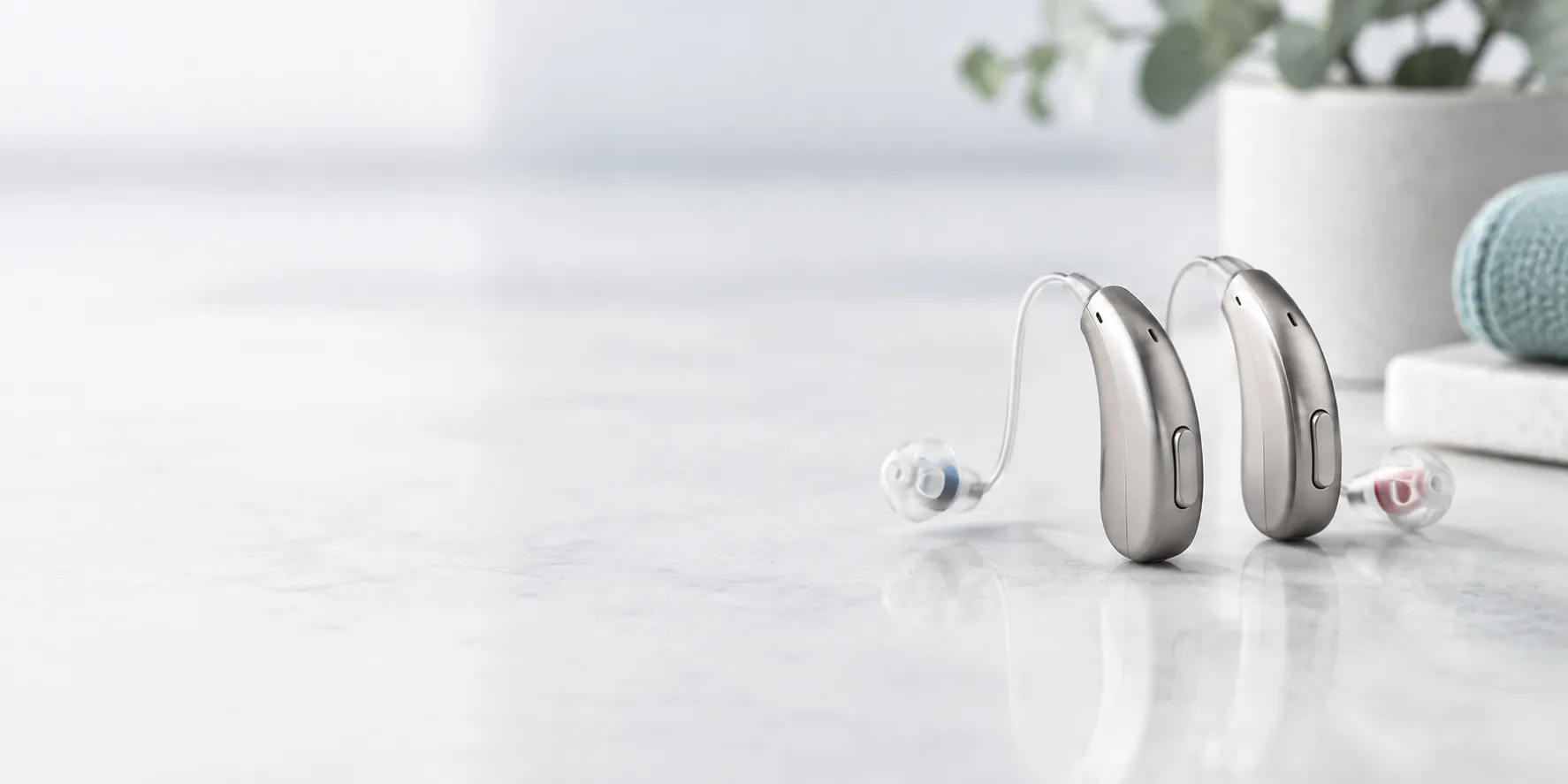 A pair of receiver-in-canal hearing aids on a white table